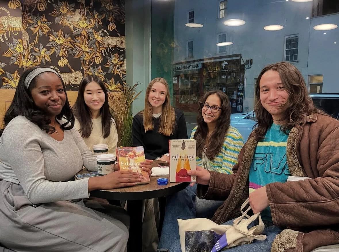 Friends around a café table holding up copies of the same book