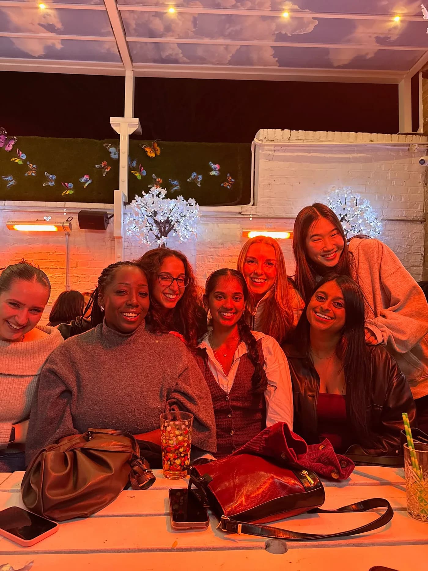 Friends smiling together around a table on a warm-lit evening